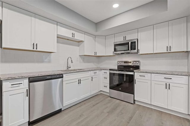 3236 Henderson Mill Rd Unit 5, Atlanta, GA 30341 - kitchen featuring appliances with stainless steel finishes, white cabinets, light wood-type flooring, and recessed lighting
