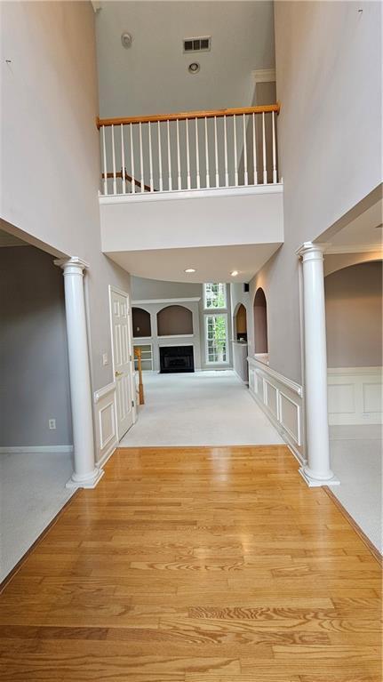 2819 Heritage Oaks Cir, Dacula, GA 30019 - entrance foyer with wood finished floors, a fireplace, a towering ceiling, and ornate columns