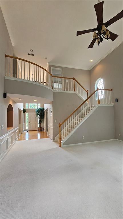 2819 Heritage Oaks Cir, Dacula, GA 30019 - unfurnished living room with healthy amount of natural light, stairway, ornamental molding, carpet flooring, and a high ceiling