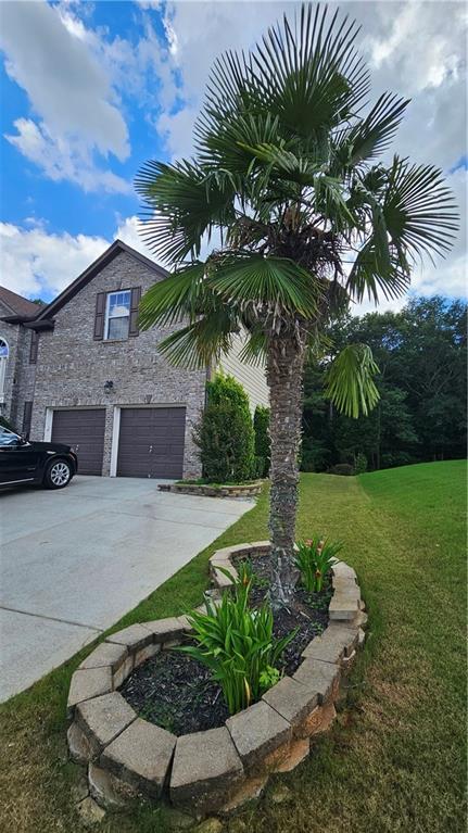 2819 Heritage Oaks Cir, Dacula, GA 30019 - view of side of home featuring a garage, stone siding, concrete driveway, and a yard