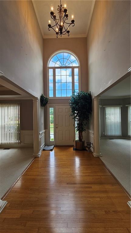 2819 Heritage Oaks Cir, Dacula, GA 30019 - entrance foyer featuring a towering ceiling, a chandelier, crown molding, wood finished floors, and a wainscoted wall