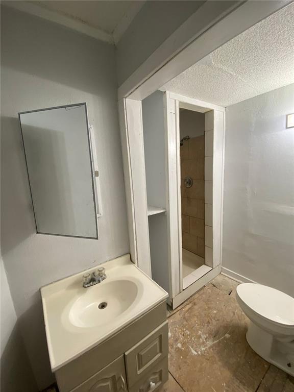 bathroom featuring toilet, vanity, and tiled shower