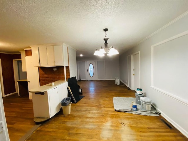 kitchen with white cabinets, light hardwood / wood-style flooring, an inviting chandelier, and hanging light fixtures