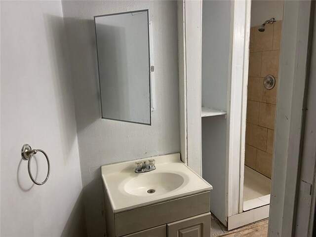 bathroom featuring tiled shower and vanity