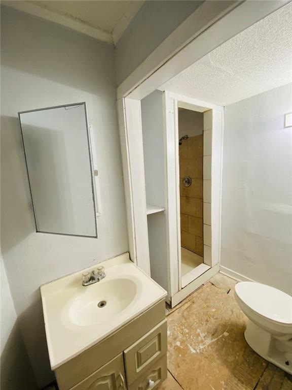 bathroom featuring toilet, vanity, and tiled shower