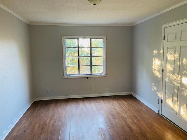 spare room featuring a textured ceiling, dark hardwood / wood-style flooring, and crown molding