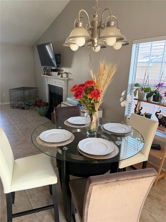 dining room featuring a chandelier, lofted ceiling, and a fireplace