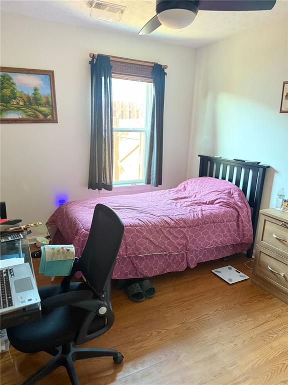 bedroom with light wood finished floors, visible vents, and a ceiling fan