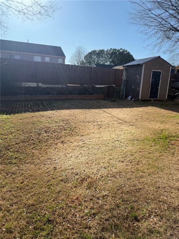 view of yard with an outbuilding, a storage unit, and a fenced backyard