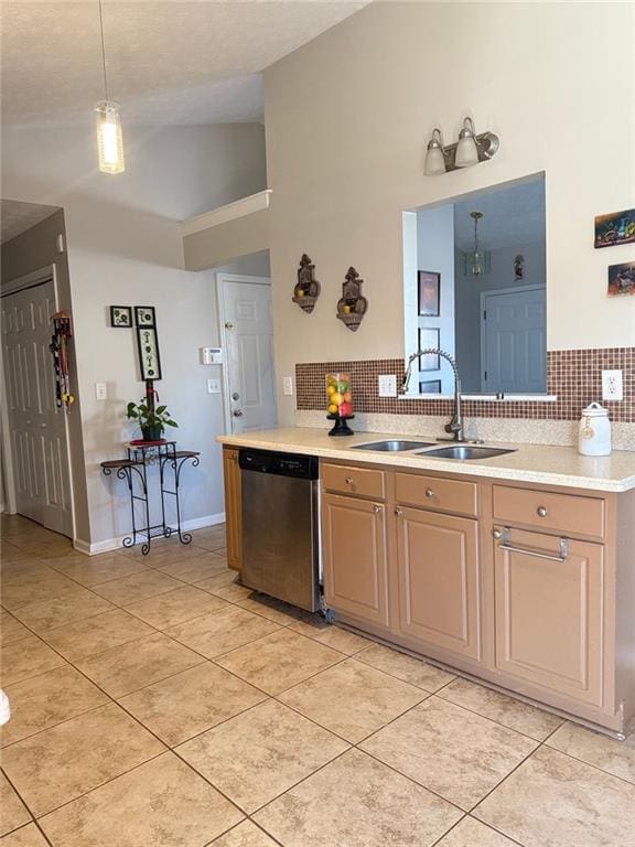 kitchen with light tile patterned floors, a sink, light countertops, stainless steel dishwasher, and decorative light fixtures