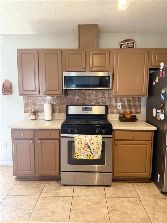 kitchen featuring appliances with stainless steel finishes, light tile patterned floors, light countertops, and tasteful backsplash