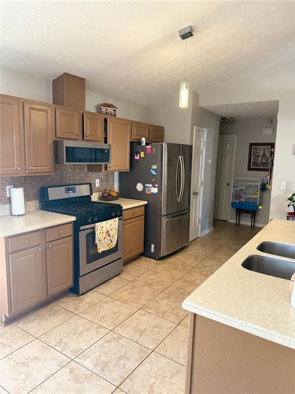 kitchen featuring appliances with stainless steel finishes, light countertops, and decorative light fixtures