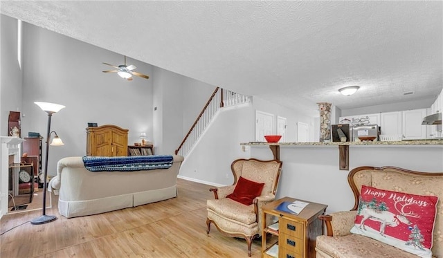190 Crestworth Ct, Powder Springs, GA 30127 - living room featuring a textured ceiling, light wood-type flooring, ceiling fan, stairway, and baseboards