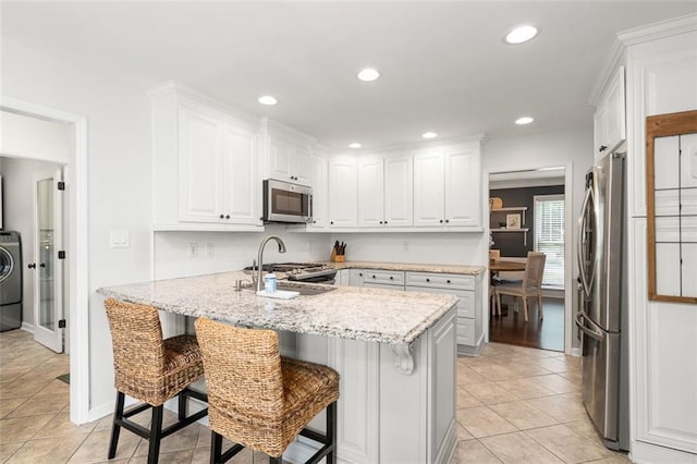 3710 Robinson Walk Ct, Marietta, GA 30068 - kitchen with appliances with stainless steel finishes, white cabinets, washer / dryer, a kitchen bar, and light tile patterned flooring