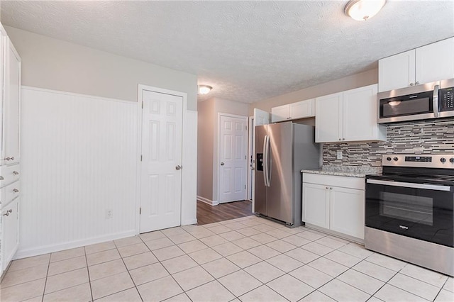 1797 Emerson Lake Cir, Snellville, GA 30078 - kitchen with stainless steel appliances, white cabinets, light tile patterned floors, backsplash, and a textured ceiling