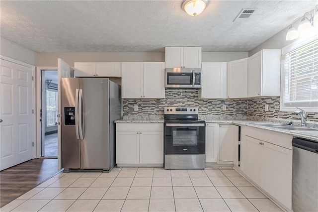 1797 Emerson Lake Cir, Snellville, GA 30078 - kitchen with stainless steel appliances, plenty of natural light, white cabinetry, tasteful backsplash, and a textured ceiling