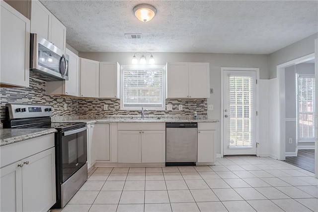 1797 Emerson Lake Cir, Snellville, GA 30078 - kitchen featuring stainless steel appliances, tasteful backsplash, white cabinets, light tile patterned floors, and a textured ceiling