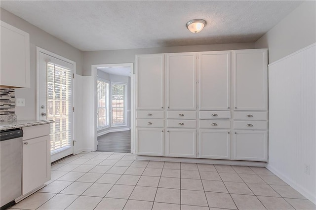 1797 Emerson Lake Cir, Snellville, GA 30078 - kitchen with stainless steel dishwasher, white cabinetry, a textured ceiling, and light tile patterned floors