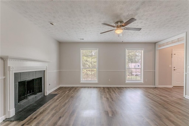 1797 Emerson Lake Cir, Snellville, GA 30078 - unfurnished living room featuring wood finished floors, ceiling fan, plenty of natural light, a tiled fireplace, and a textured ceiling