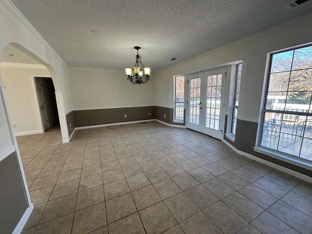 unfurnished dining area with a chandelier, french doors, a textured ceiling, and crown molding