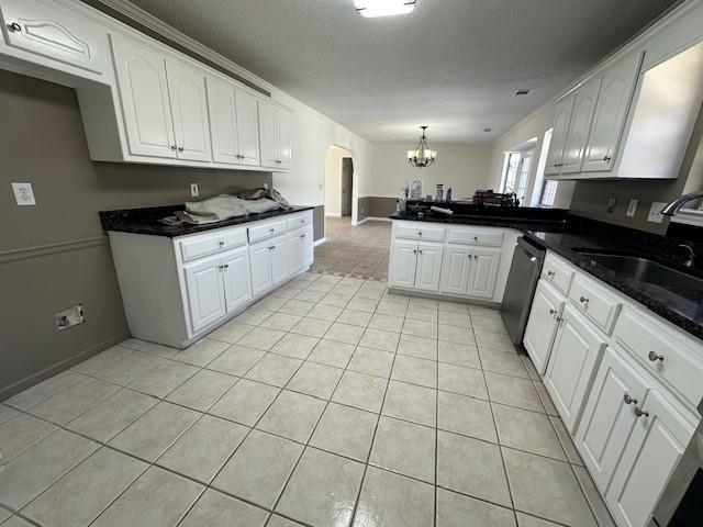 kitchen with white cabinetry, sink, hanging light fixtures, stainless steel dishwasher, and kitchen peninsula