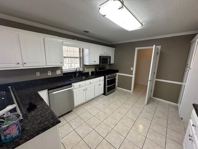 kitchen featuring white cabinets, stainless steel appliances, crown molding, and sink