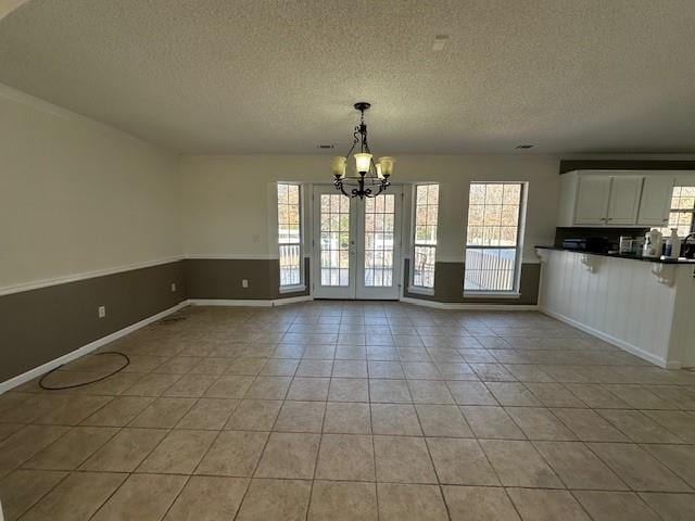 unfurnished dining area with light tile patterned floors, a textured ceiling, and a notable chandelier