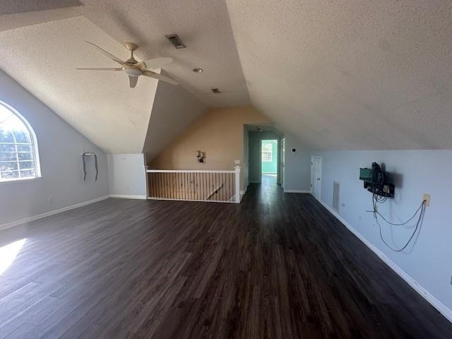 additional living space with a textured ceiling, dark hardwood / wood-style floors, ceiling fan, and lofted ceiling