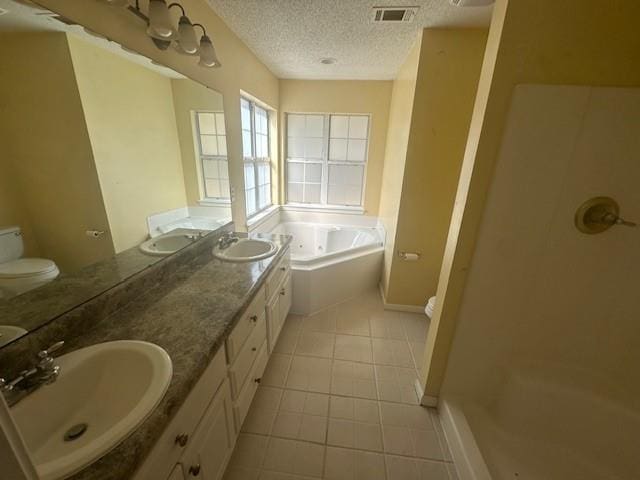 bathroom featuring a tub to relax in, vanity, a textured ceiling, tile patterned flooring, and toilet