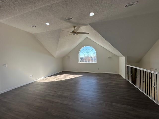 additional living space featuring ceiling fan, dark hardwood / wood-style flooring, a textured ceiling, and vaulted ceiling