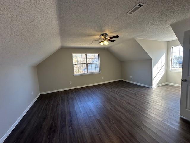 bonus room featuring a textured ceiling, lofted ceiling, ceiling fan, and dark hardwood / wood-style floors