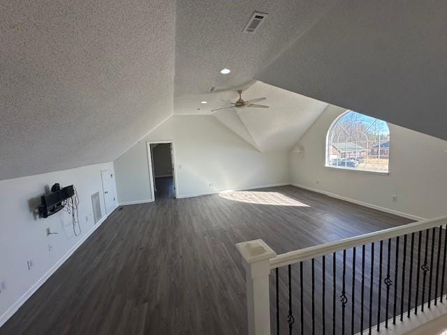 bonus room with ceiling fan, dark hardwood / wood-style flooring, a textured ceiling, and vaulted ceiling