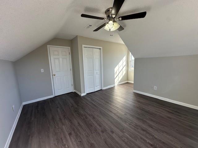 bonus room featuring vaulted ceiling, a textured ceiling, and dark hardwood / wood-style floors