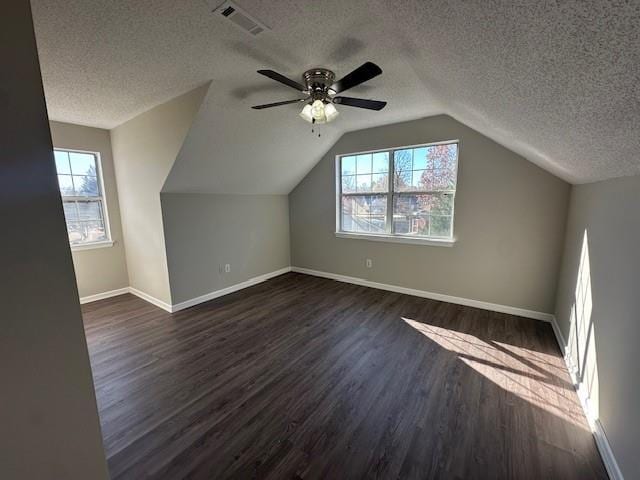 additional living space with vaulted ceiling, ceiling fan, dark wood-type flooring, and a textured ceiling