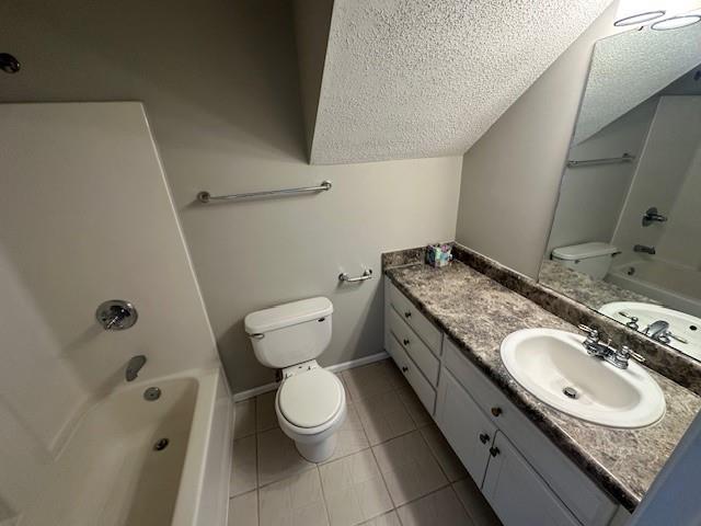 full bathroom featuring tile patterned floors, a textured ceiling, toilet, shower / washtub combination, and vanity