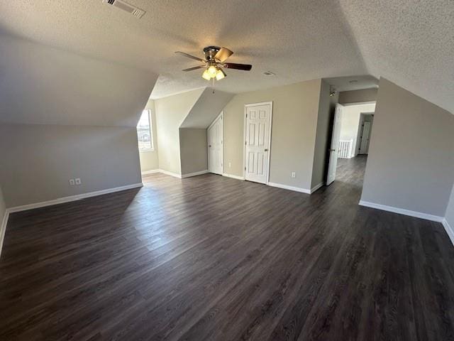 bonus room with a textured ceiling, vaulted ceiling, and dark hardwood / wood-style floors