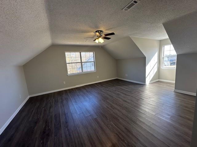 bonus room with a textured ceiling, ceiling fan, dark wood-type flooring, and vaulted ceiling