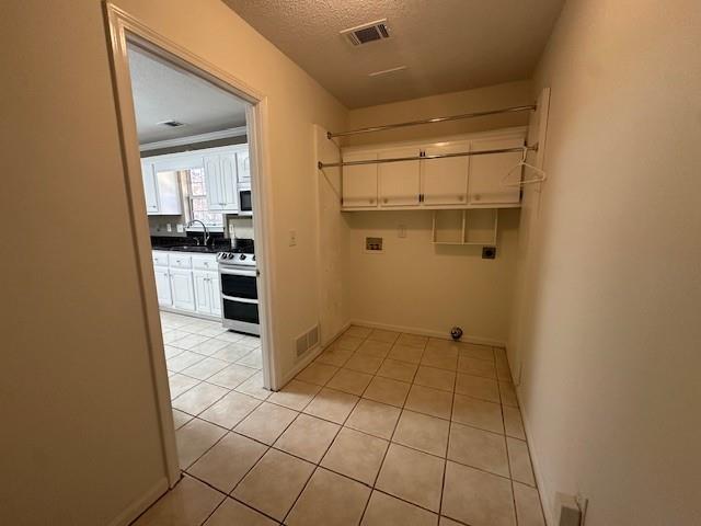 laundry area featuring hookup for an electric dryer, washer hookup, a textured ceiling, sink, and light tile patterned flooring