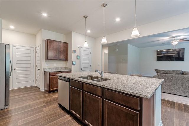 kitchen with a center island with sink, appliances with stainless steel finishes, hanging light fixtures, dark hardwood / wood-style flooring, and sink