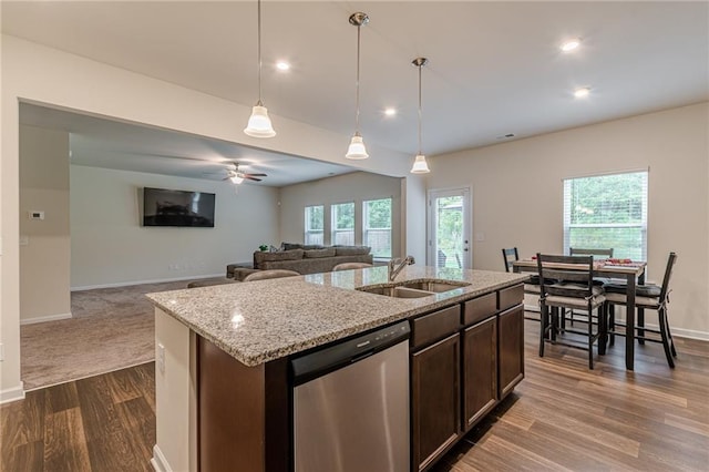 kitchen featuring light stone countertops, pendant lighting, sink, dark brown cabinets, and stainless steel dishwasher