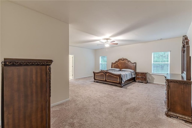 bedroom featuring ceiling fan, multiple windows, and light carpet