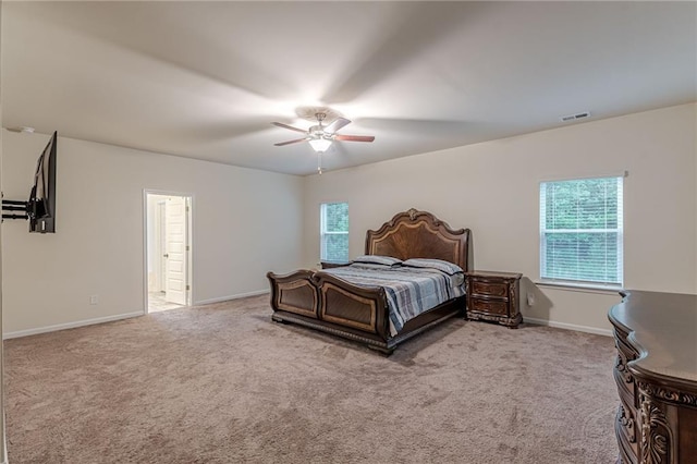 carpeted bedroom with ensuite bathroom and ceiling fan