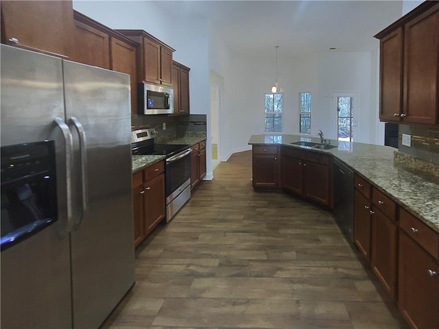 kitchen featuring sink, hanging light fixtures, stainless steel appliances, light stone countertops, and decorative backsplash