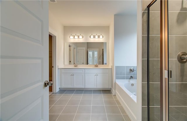 full bath with tile patterned floors, a bath, double vanity, and a sink