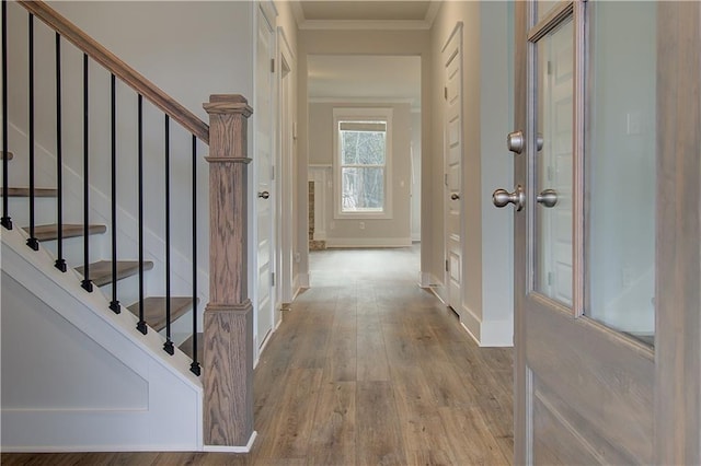 corridor with stairs, wood finished floors, baseboards, and ornamental molding