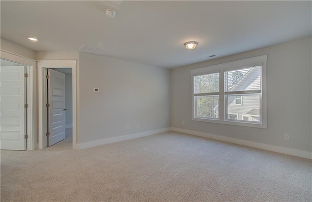 spare room featuring visible vents, light carpet, and baseboards