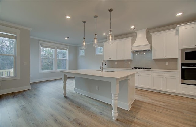 kitchen featuring ornamental molding, custom range hood, a sink, tasteful backsplash, and gas stovetop