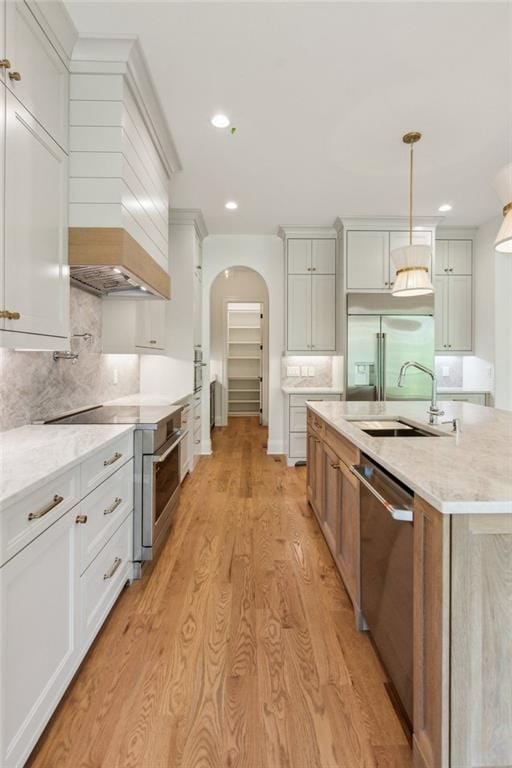 7188 Williams Rd, Flowery Branch, GA 30542 - kitchen with premium appliances, a sink, arched walkways, light wood-type flooring, and recessed lighting
