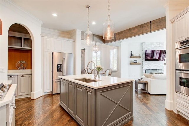 kitchen with stainless steel appliances, a sink, white cabinetry, light countertops, and an island with sink