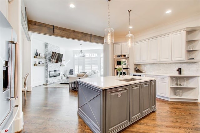 kitchen featuring light countertops, hanging light fixtures, a kitchen island with sink, and white cabinets